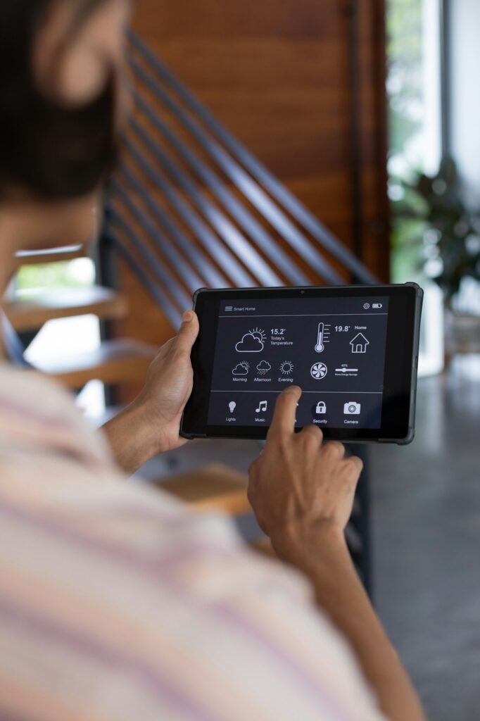 Vertical of hands of biracial man at home using tablet with smart home interface, copy space
